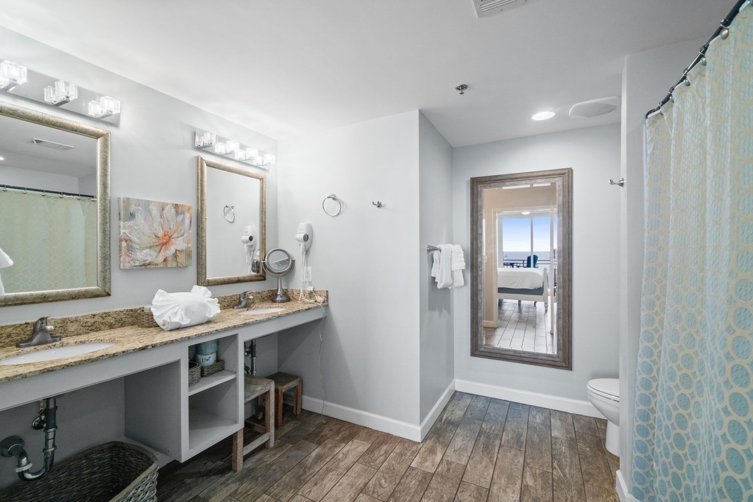A bathroom with a large mirror, vanity, and a shower curtain.