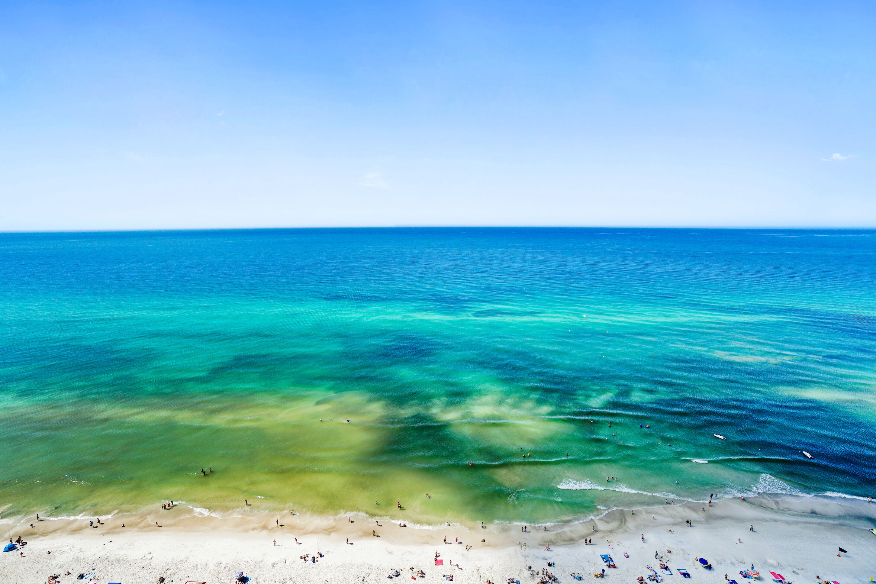 Ein Strand mit klarem türkisblauem Wasser und einem sandigen Ufer.