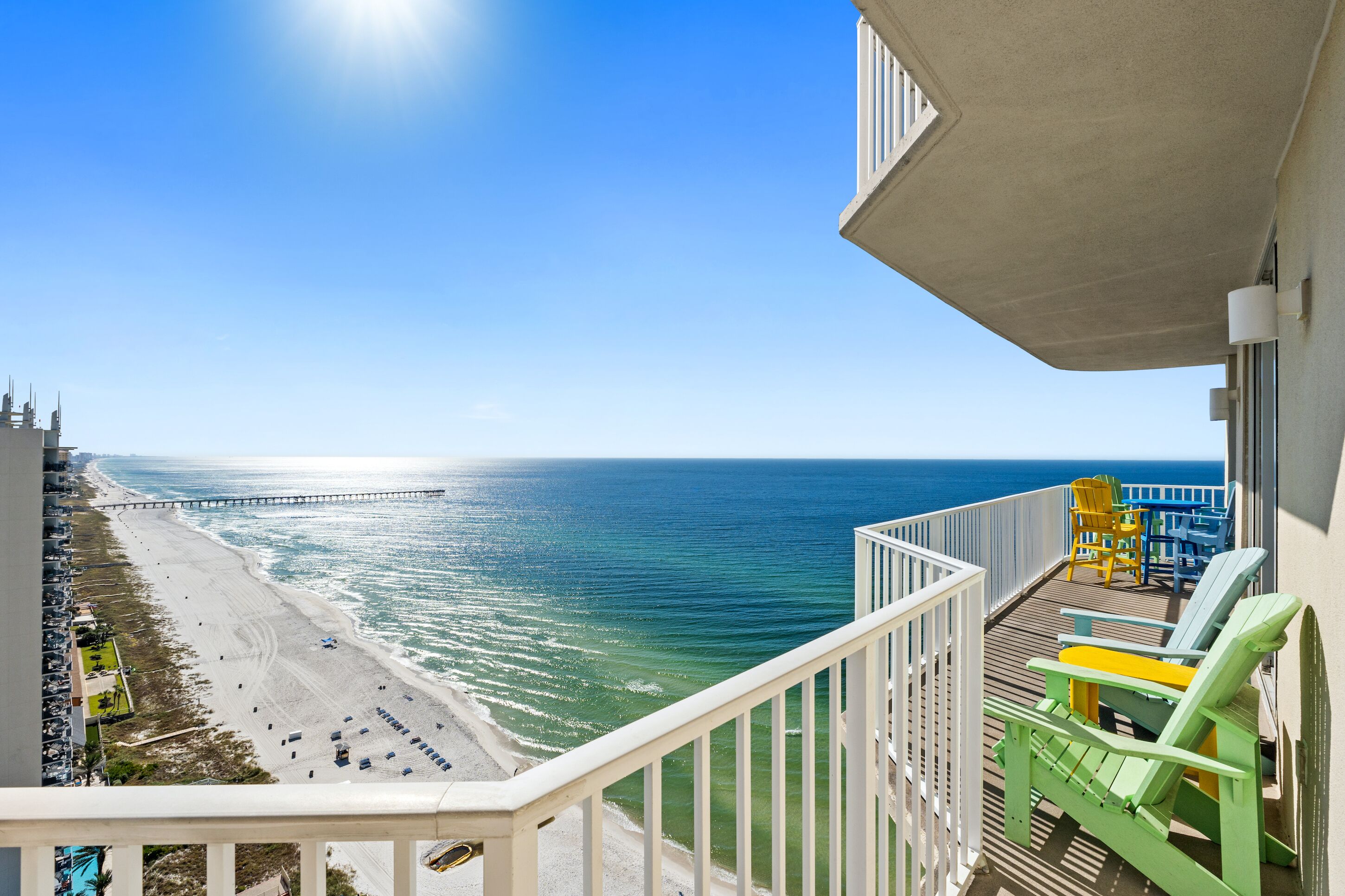 A balcony with a view of a beach and a pier.