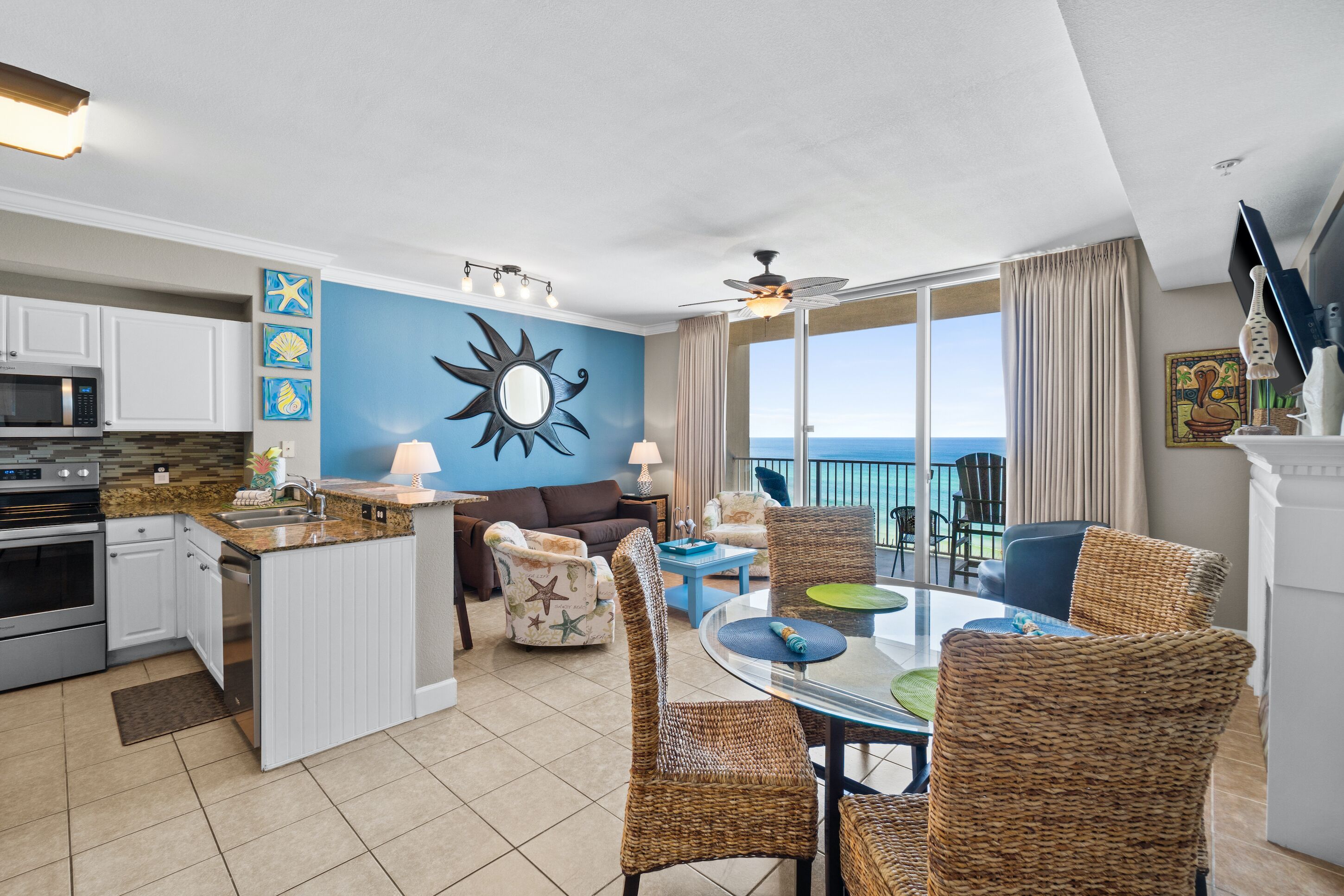 A spacious living area with a kitchen, dining table, and a balcony with a view of the ocean.