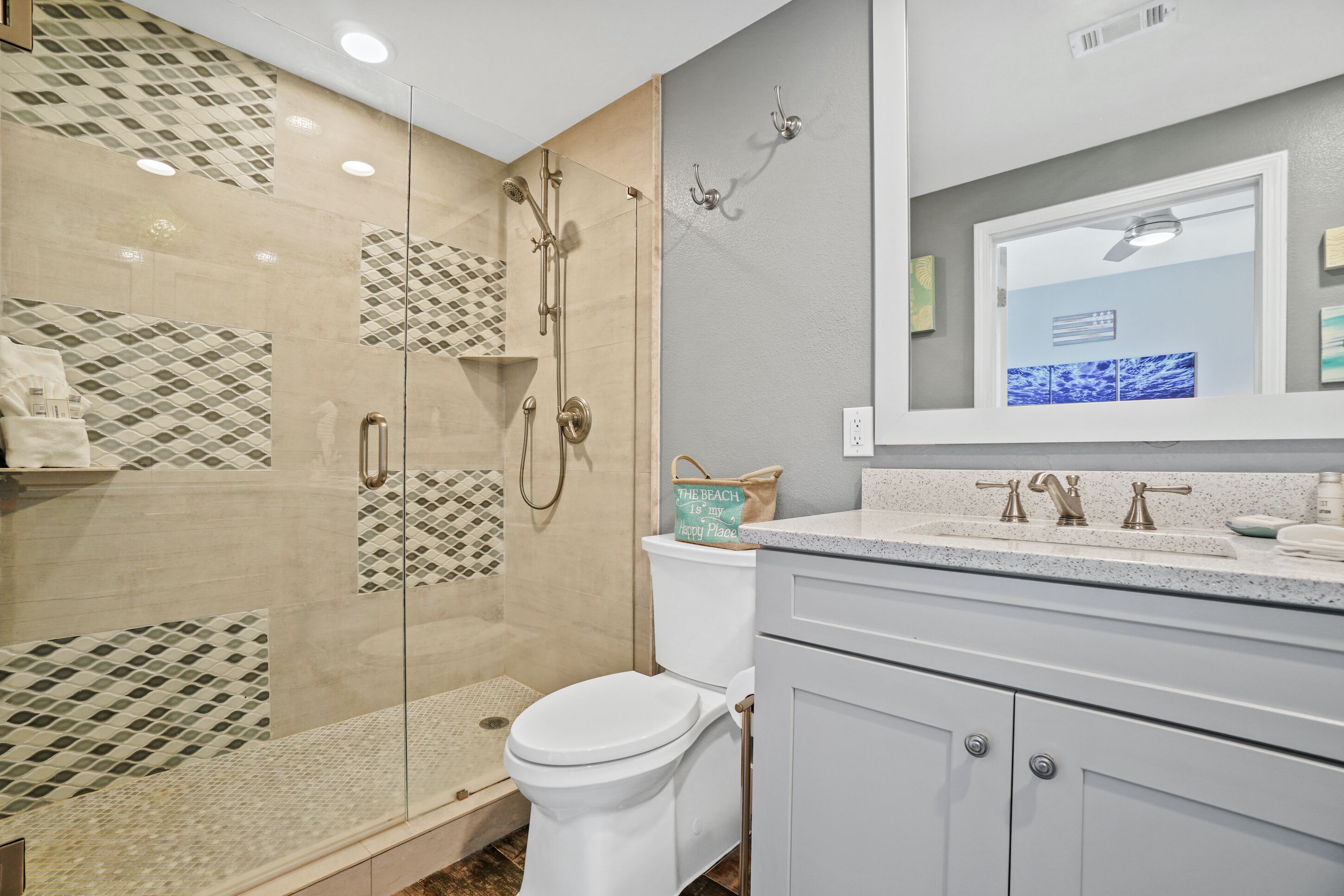 A modern bathroom with a glass-enclosed shower, a toilet, and a vanity with a sink and mirror.