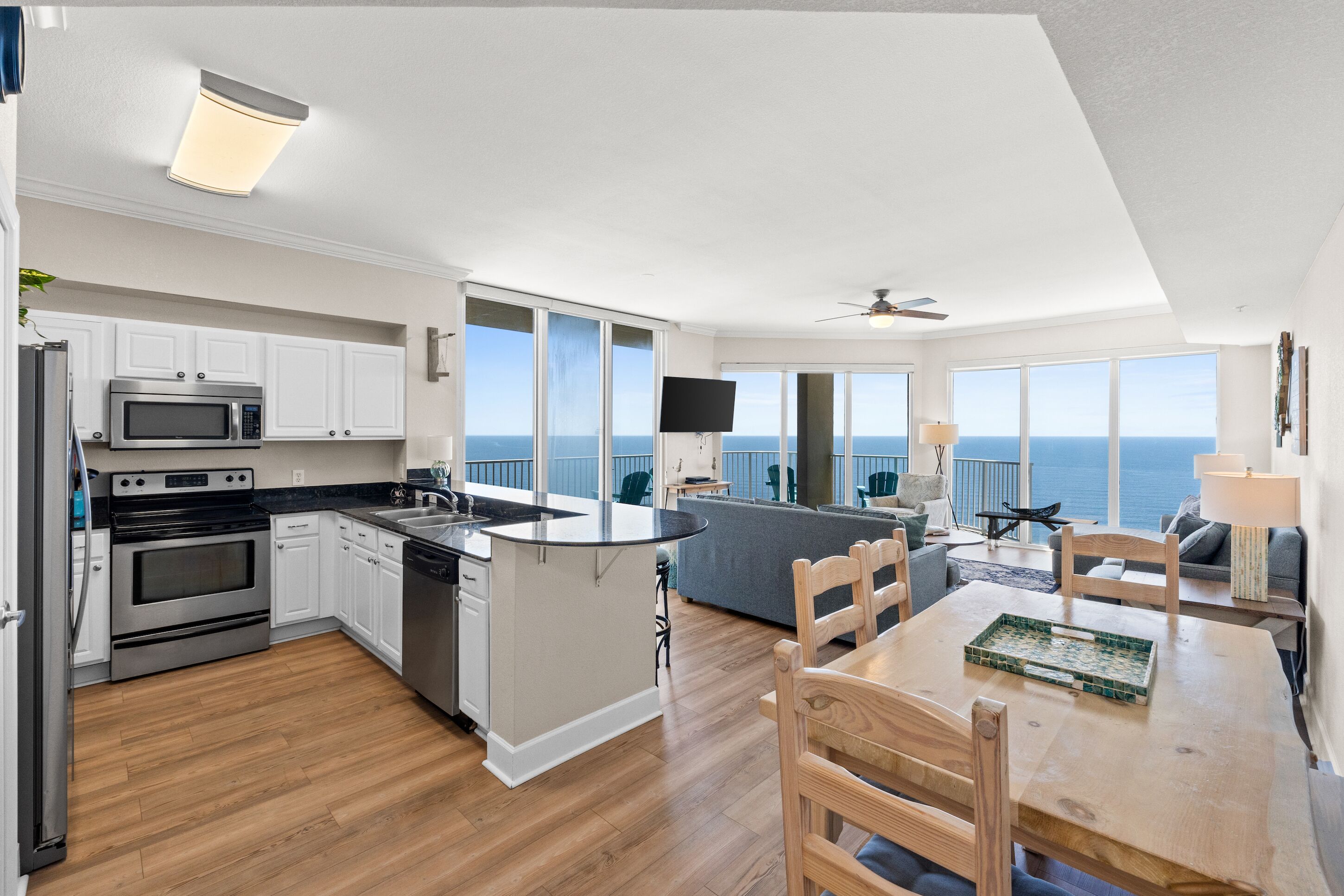 A modern kitchen with white cabinets, stainless steel appliances, and a large island.