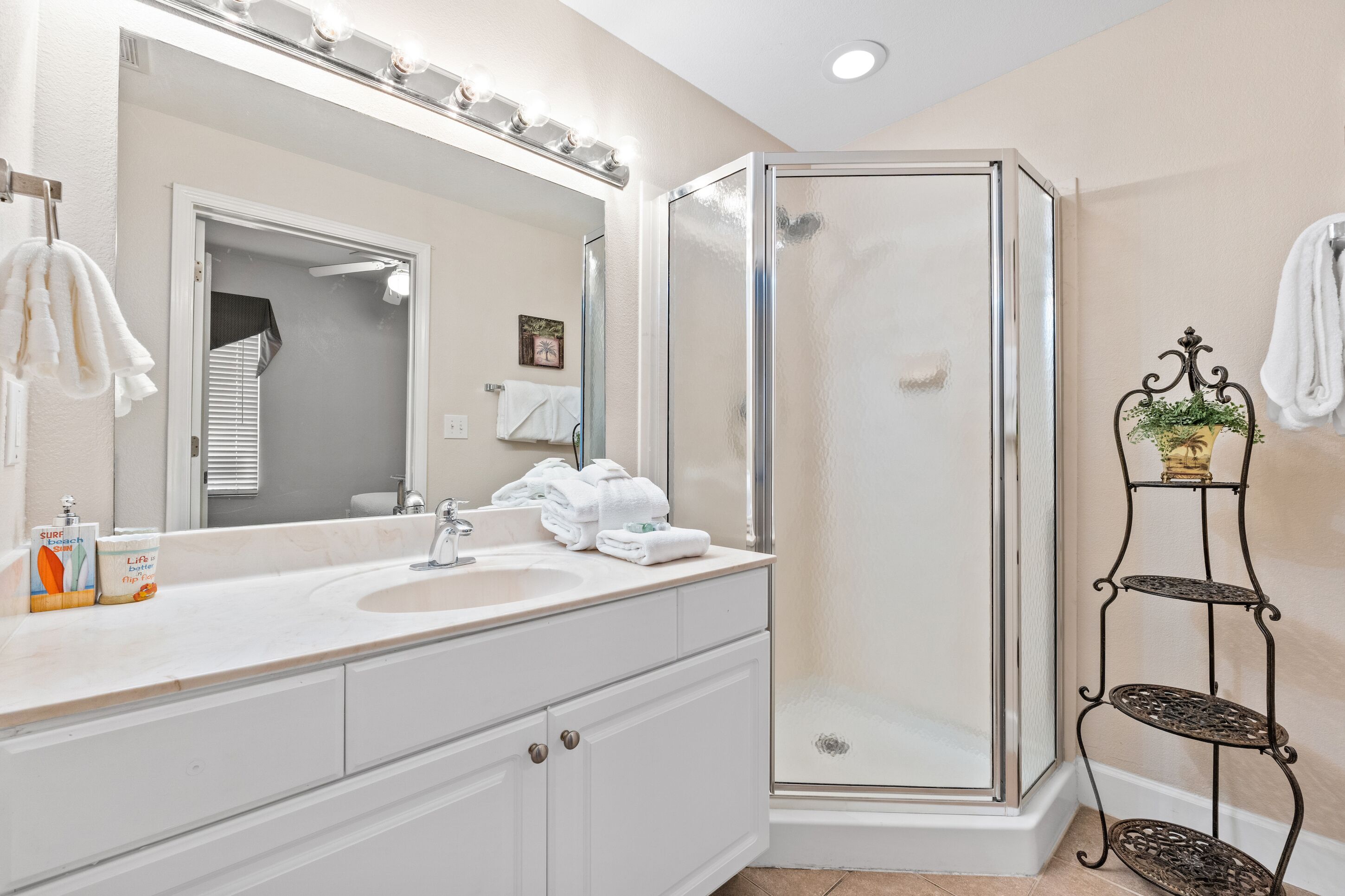 A bathroom with a large mirror, two sinks, a shower enclosure, and a towel rack.