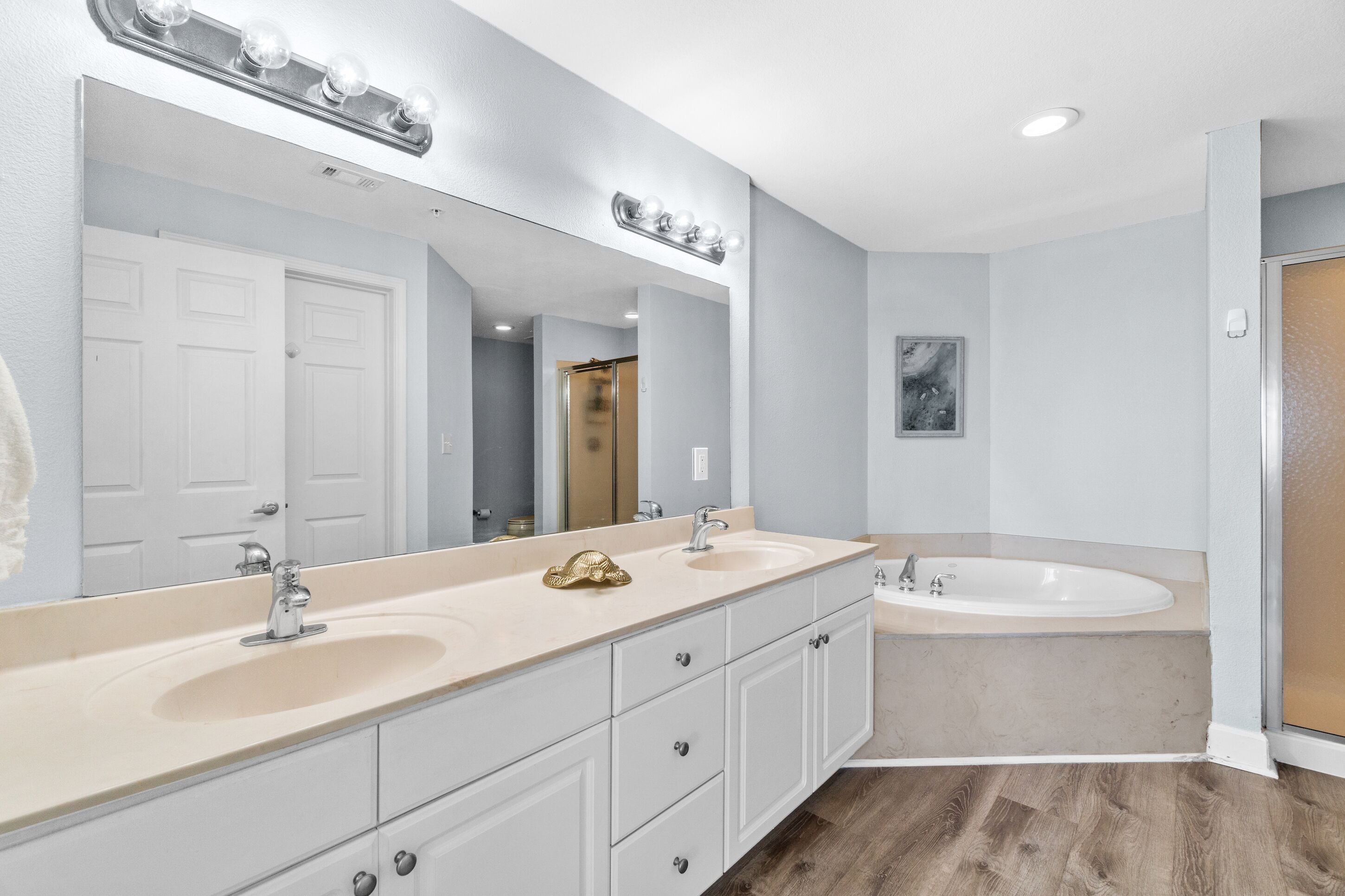 Une salle de bain avec deux lavabos, un grand miroir et une baignoire.