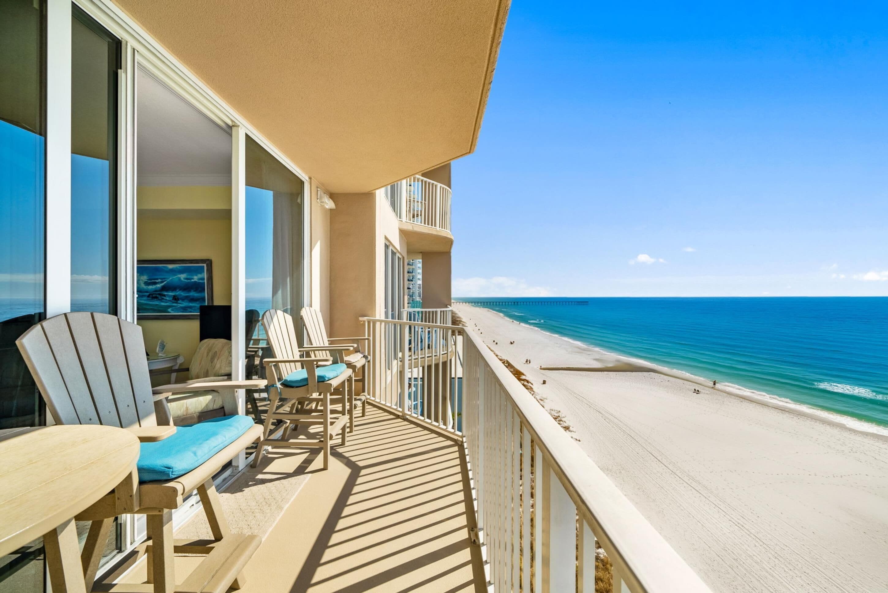 A balcony with a view of the beach, featuring a table and chairs.