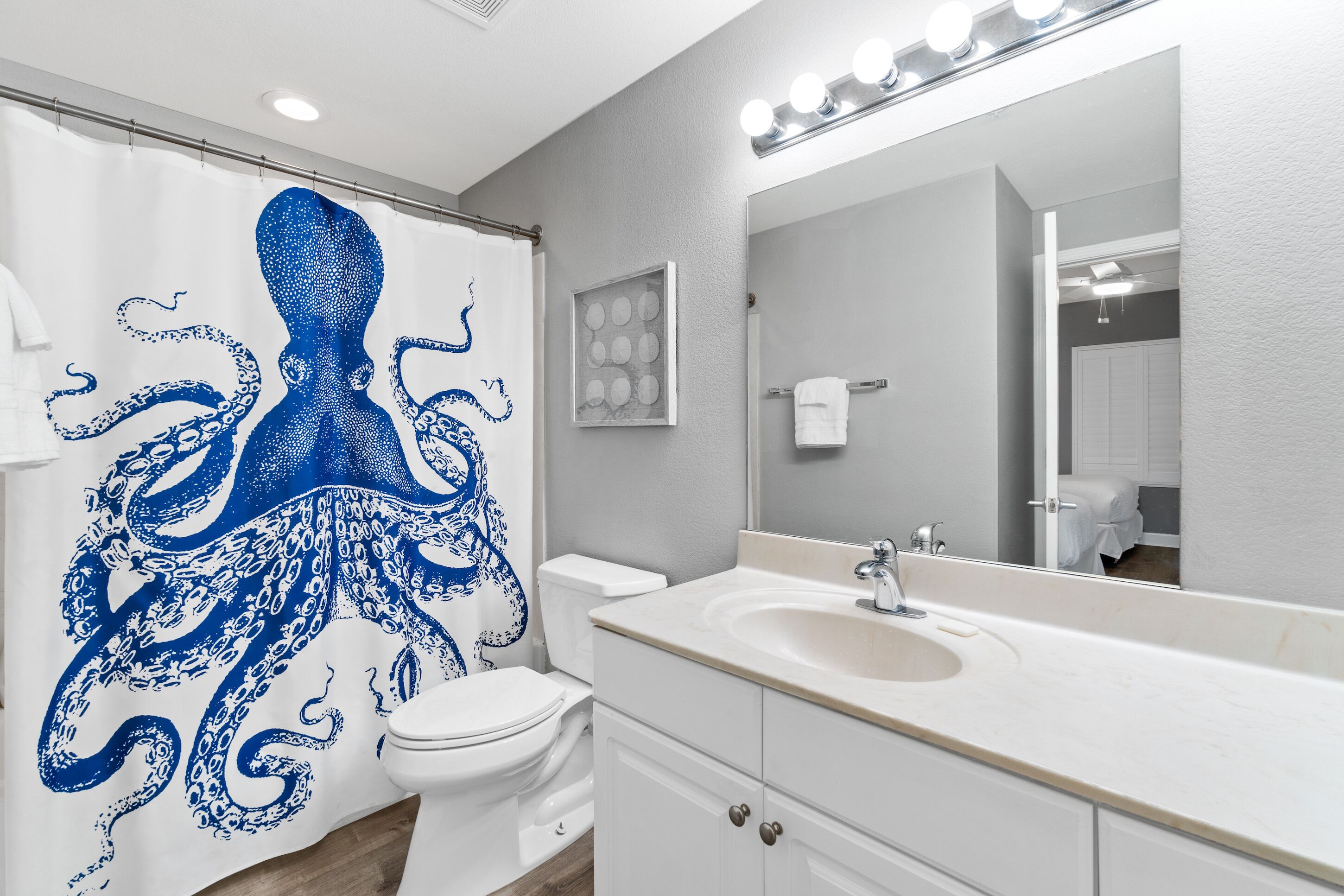 A bathroom with a white sink, a mirror, and a shower curtain with a blue octopus design.