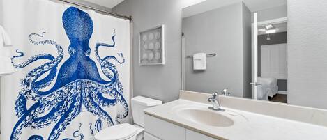 A bathroom with a white sink, a mirror, and a shower curtain with a blue octopus design.