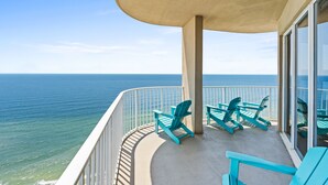 Un balcon avec vue sur l’océan, agrémenté de chaises turquoise et doté d’un sol en béton.