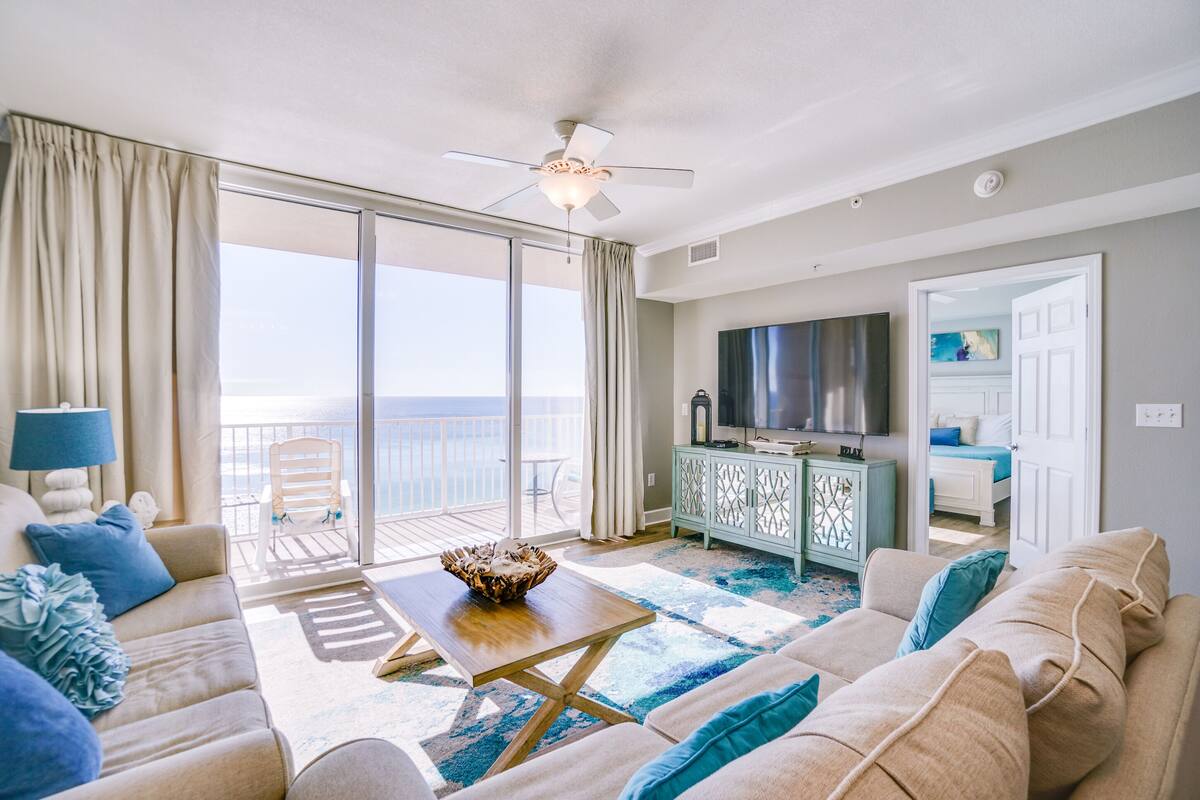 Un salon comprenant un canapé, une table basse, un téléviseur et un balcon avec vue sur l’océan.