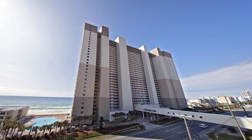 Un grand hôtel à plusieurs étages, doté d’une piscine et offrant une vue sur l’océan.