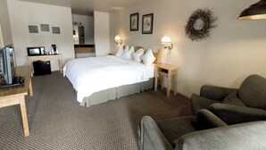 Une chambre d’hôtel avec un grand lit, un bureau avec un ordinateur, une chaise et un canapé.