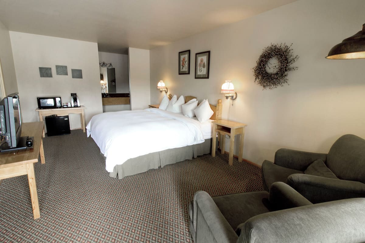 A hotel room with a large bed, a desk with a computer, a chair, and a couch.