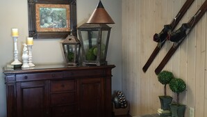 Une commode en bois avec des tiroirs, un tableau encadré, une lanterne et une paire de skis appuyés contre un mur en bois.