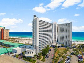 Un hotel con un patio central, varios niveles de estacionamiento y vistas a la playa.