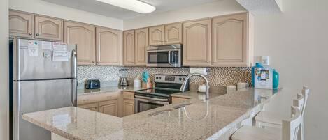 A kitchen with granite countertops, stainless steel appliances, and wooden cabinets.