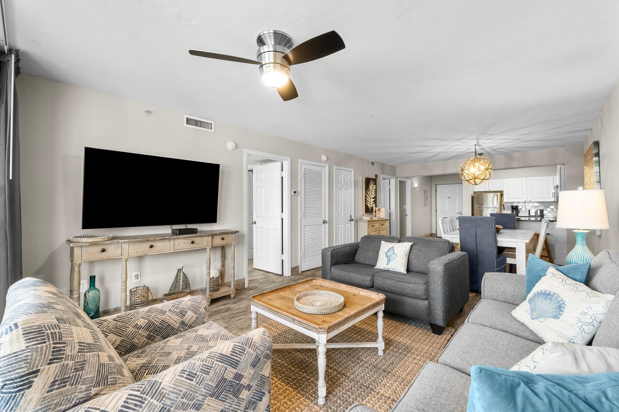A living room with a television, sofa, coffee table, and a ceiling fan.