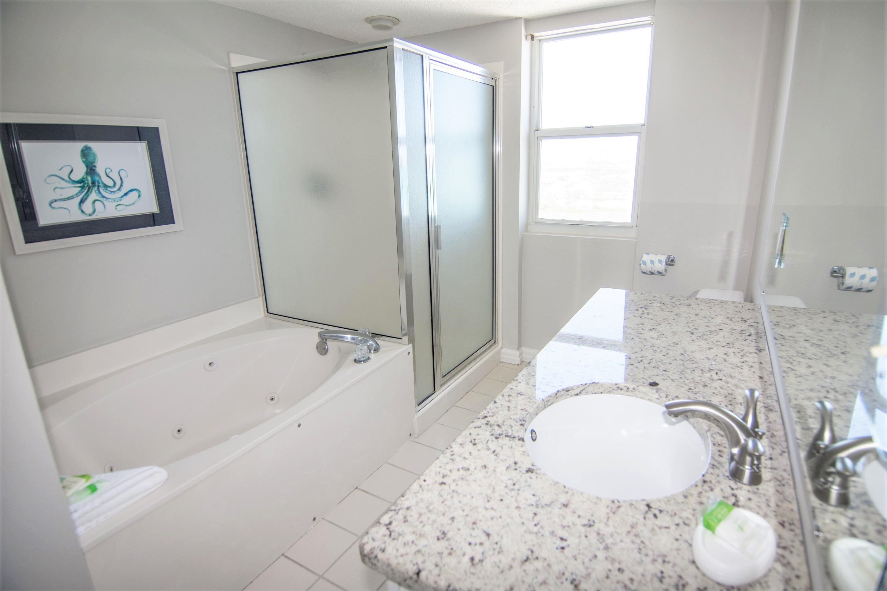 A modern bathroom with a freestanding bathtub, a double sink vanity, and a framed artwork on the wall.