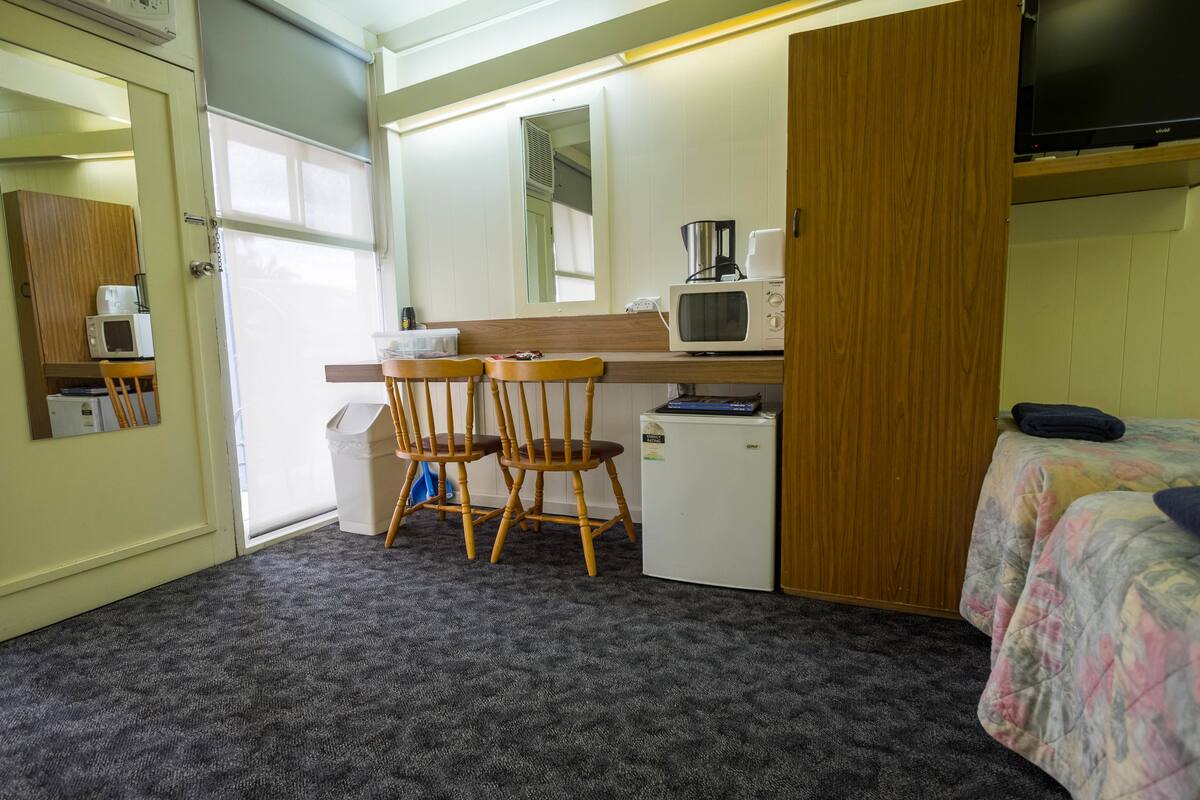A compact room with a kitchenette, a bed, and a small table with chairs.