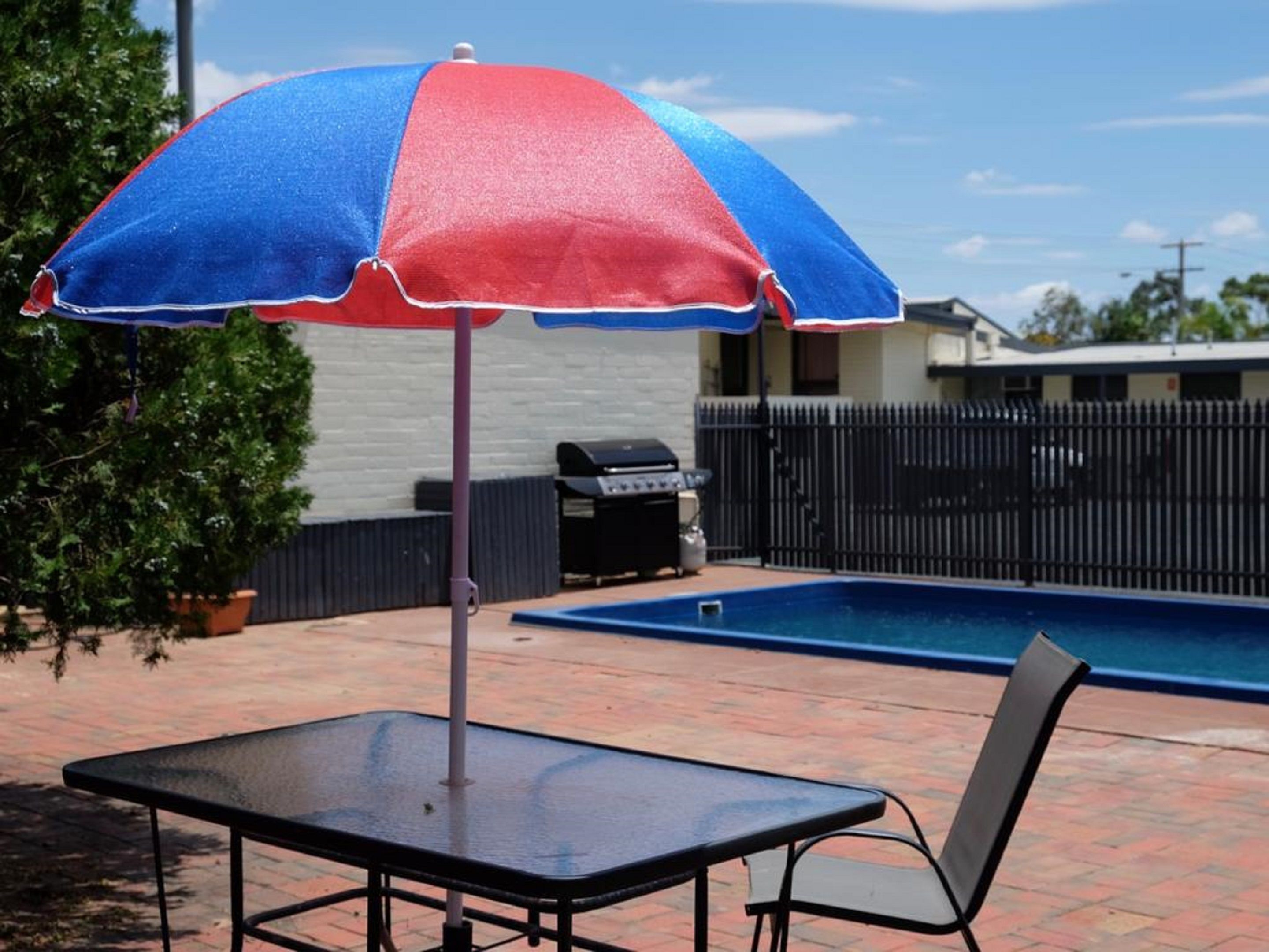 Un patio con piscina, una mesa y una sombrilla.