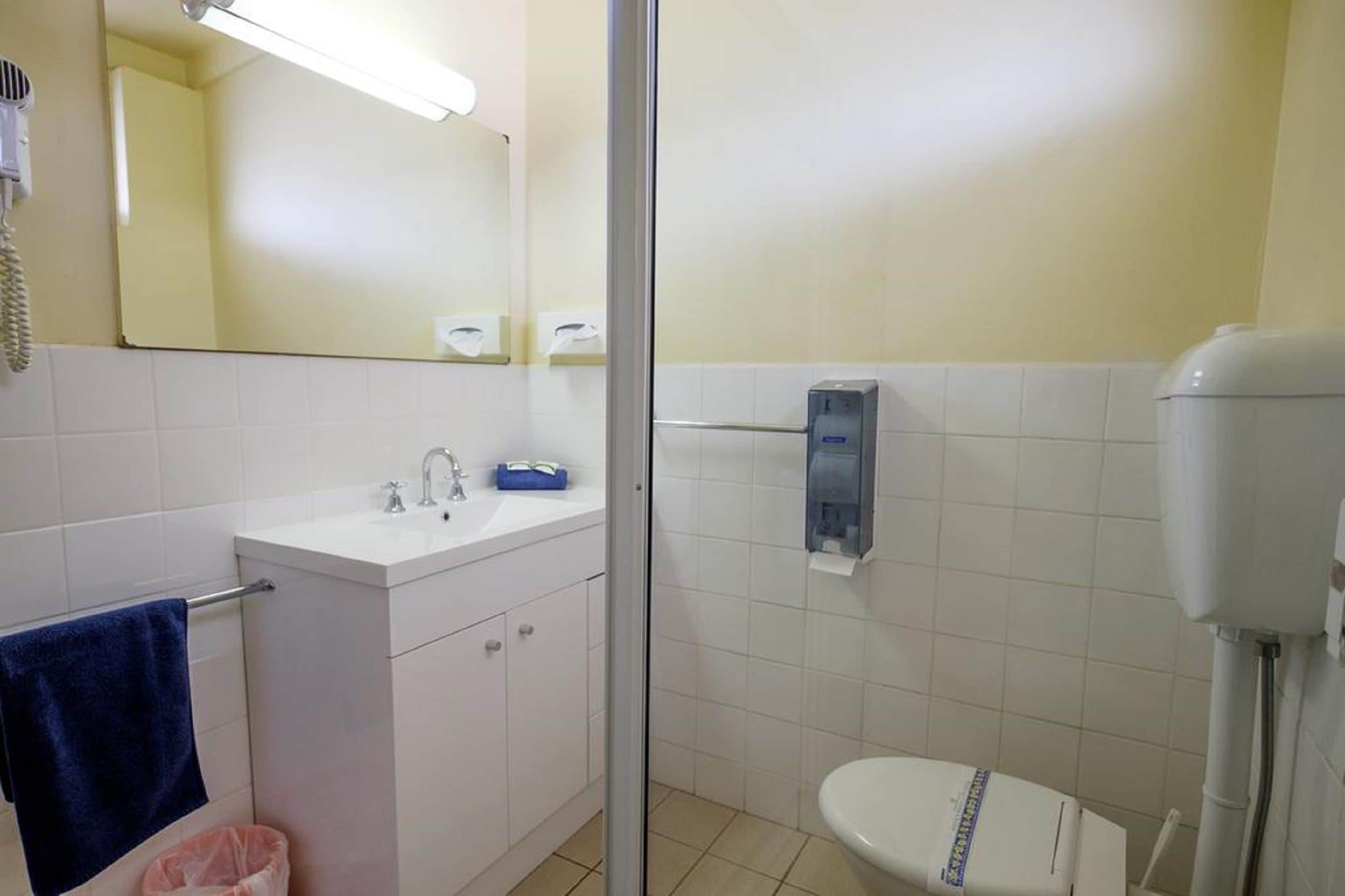 A bathroom with a white sink, mirror, and toilet.