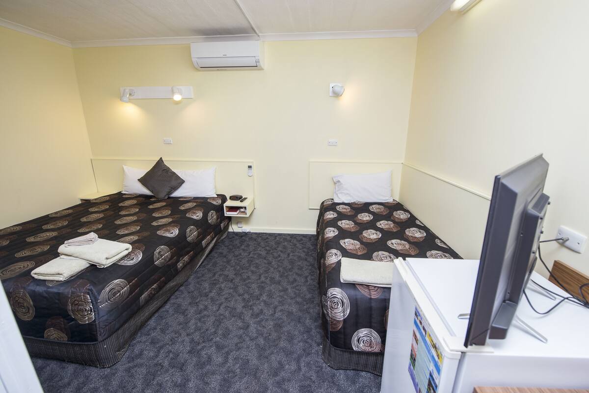 A hotel room with two beds, a television, and a small desk.