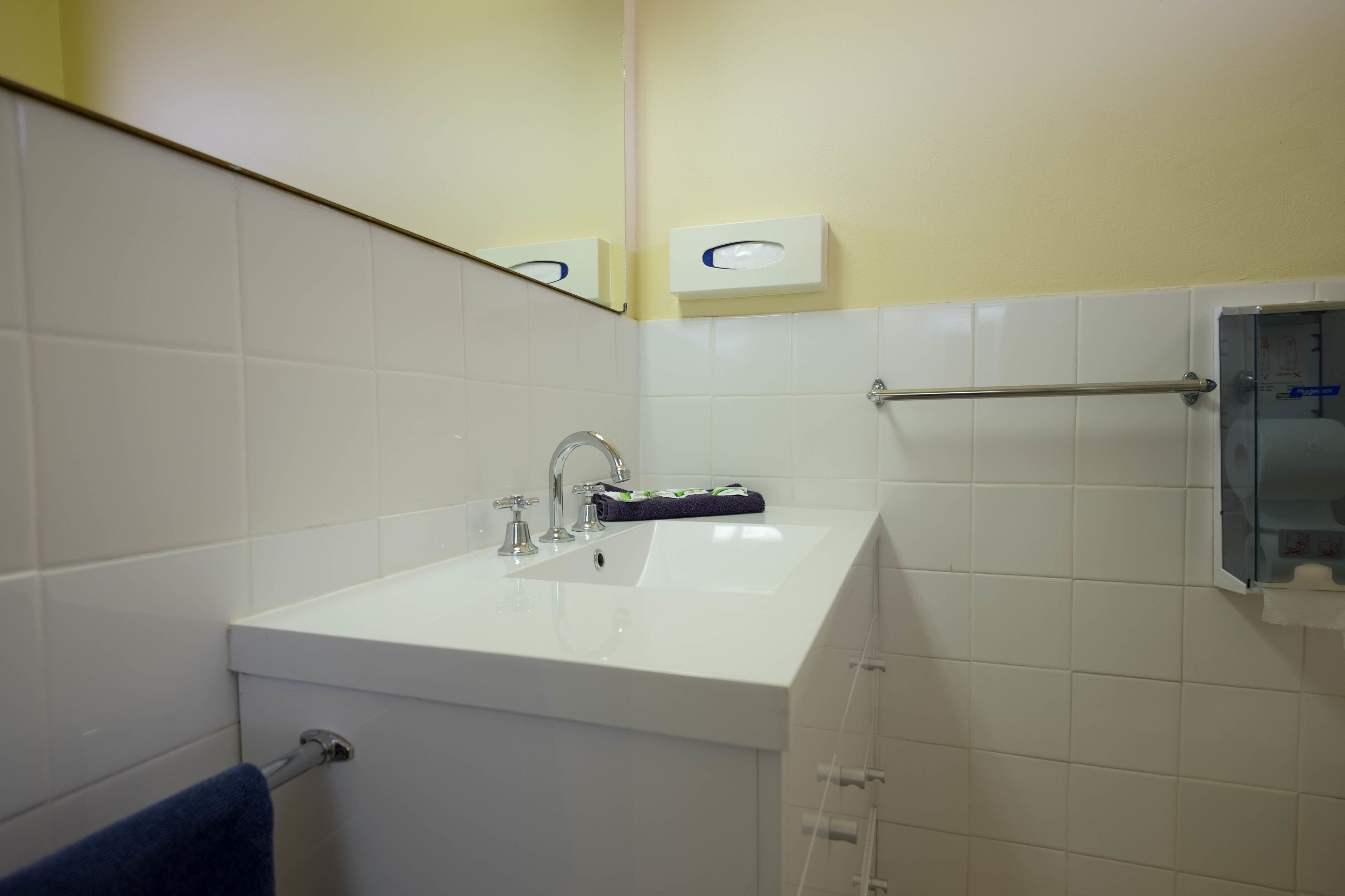 Une salle de bain avec un lavabo blanc, un miroir et un porte-serviettes.