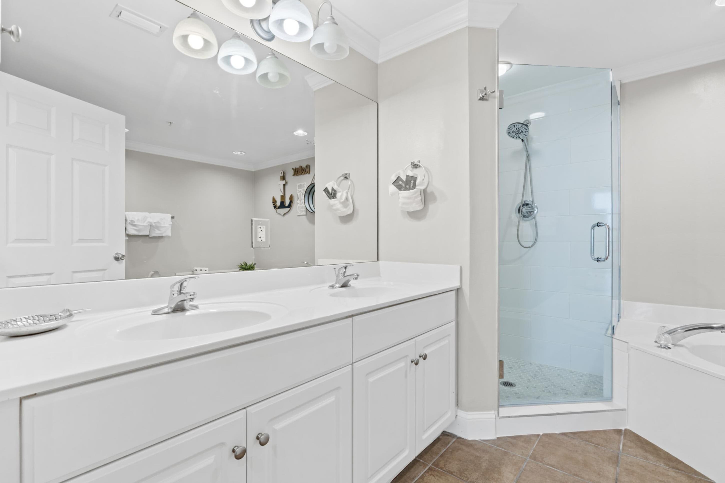 Un baño moderno con tocador doble, un espejo grande, ducha con mampara de vidrio y bañera separada.