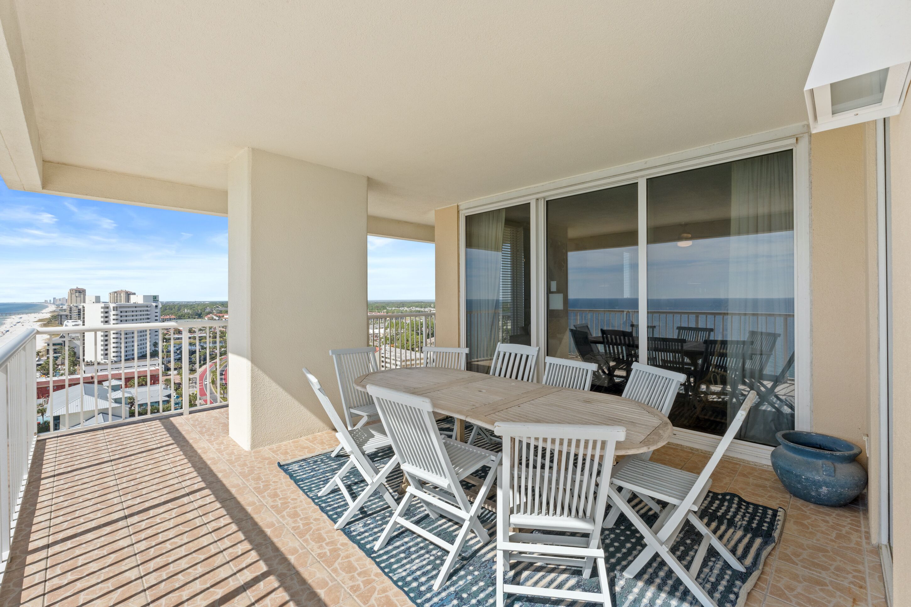 A balcony with a table and chairs, a large window, and a view of the cityscape.