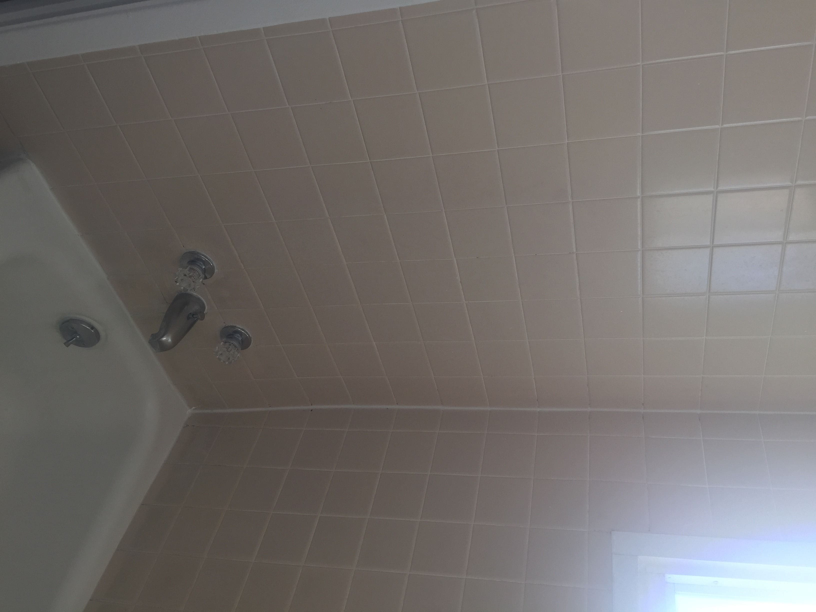 A bathroom with beige tiles, a bathtub, and a shower.