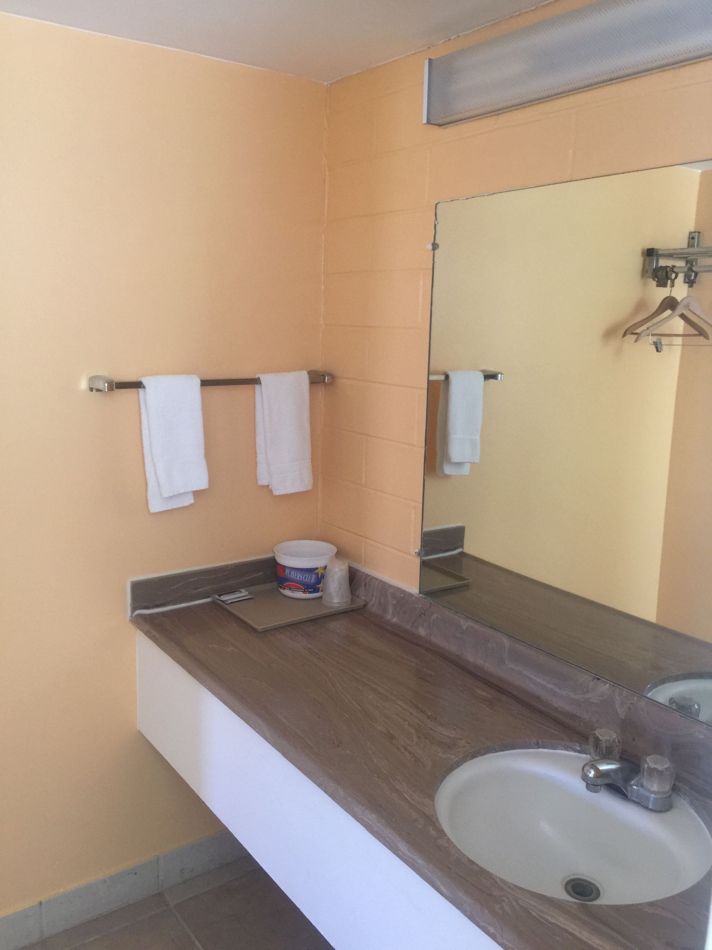 Un baño con lavabo, espejo, toallero y un cubo.