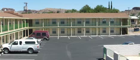 A motel with a two-story structure, a parking lot, and a mountainous backdrop.
