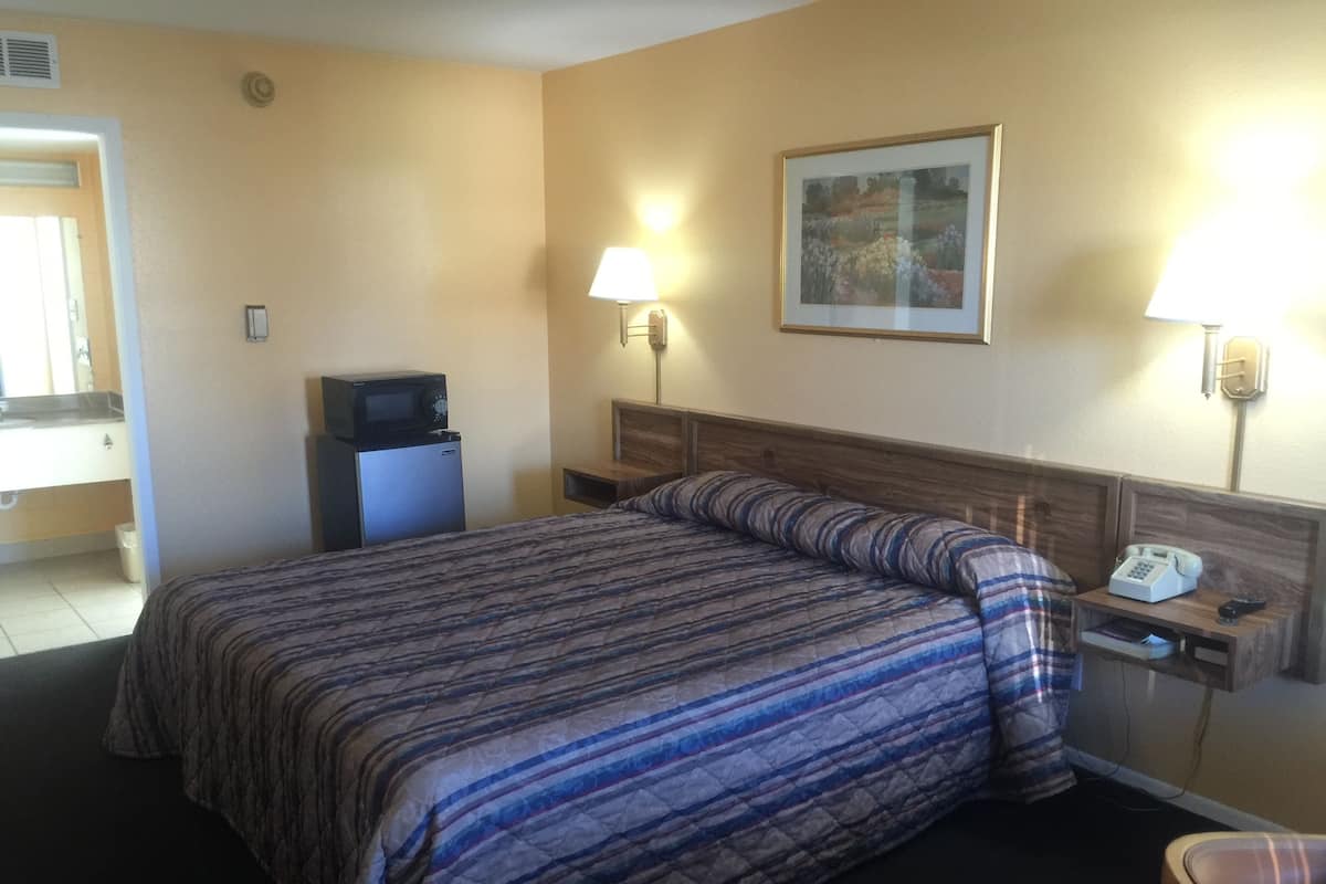 A hotel room with a bed, bedside table, lamp, and a small desk with a telephone.