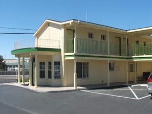 Un motel à deux étages, doté d’un balcon verdoyant au deuxième étage, d’une entrée couverte et d’un parking.