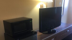 Une petite cuisine équipée d’un four à micro-ondes, d’un réfrigérateur et d’un téléviseur à écran plat, le tout installé sur un plan de travail en bois.