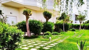 A well-maintained garden with neatly trimmed hedges, a stone pathway, and a variety of plants.
