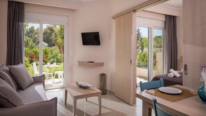 A modern hotel room with a sofa, dining table, and a television.