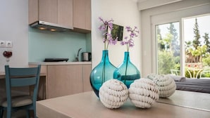 A modern kitchen with light wood cabinets, a dining table with decorative white spheres, and two blue vases with purple flowers.