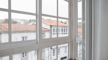 Vista a través de una ventana con entramado, mostrando edificios con tejados rojos y fachadas blancas.