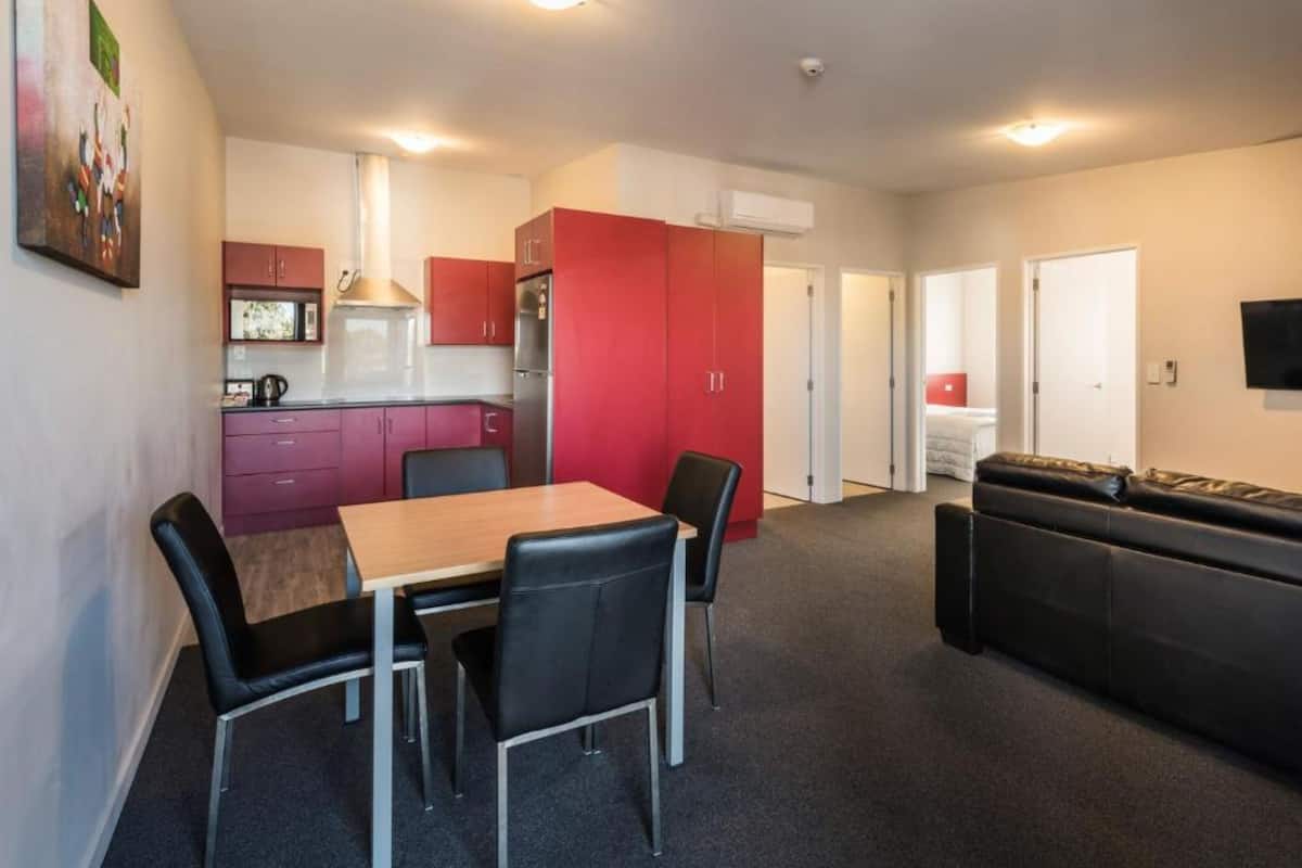 Un espacio habitable compacto con kitchenette, un comedor con mesa y sillas, y un sofá.