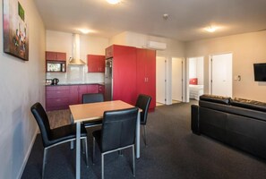 A compact living space with a kitchenette, a dining area with a table and chairs, and a sofa. - C Motel (Christchurch)