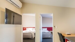 Habitación de hotel con cama, escritorio y silla. Se observa un equipo de aire acondicionado en la pared.