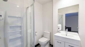 Casa de banho moderna com cabine de duche em vidro, sanita e lavatório branco com espelho em cima.