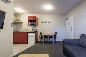 A compact living space with a kitchenette, a dining area, and a sofa. - C Motel (Christchurch)