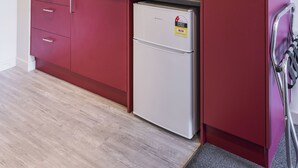 Una cocina compacta con microondas, pileta de acero inoxidable y refrigerador pequeño.