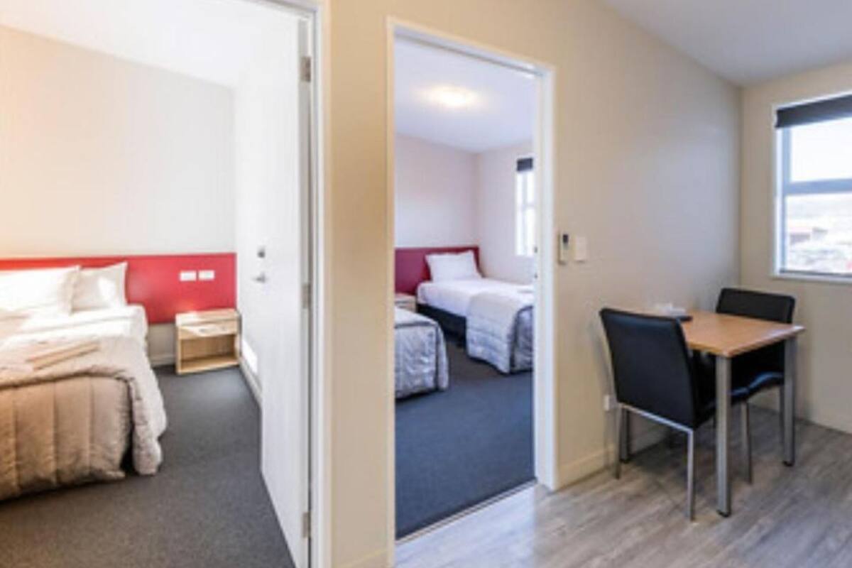 Una habitación de hotel con cama, mesita de noche y ventana.