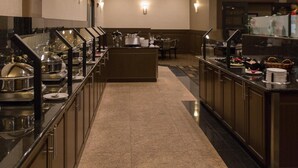 A buffet setup with multiple serving stations, a central island, and a seating area with tables and chairs.