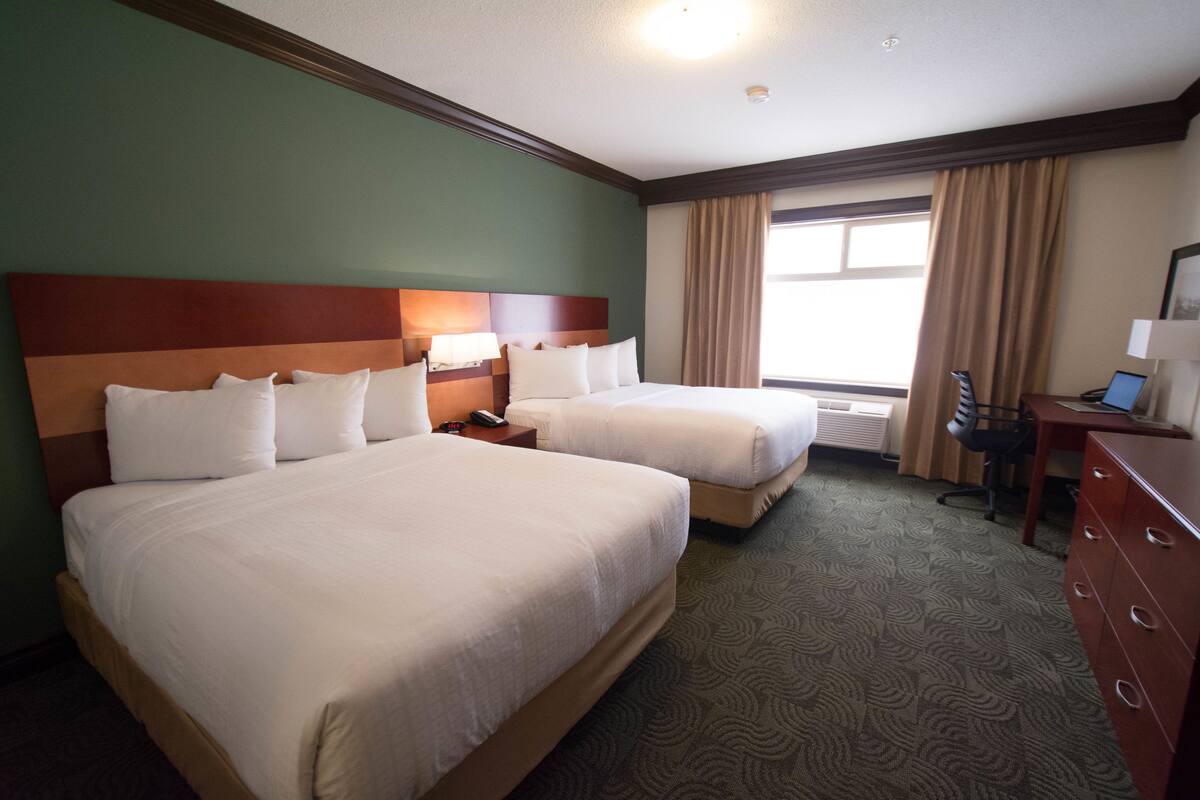 Een hotelkamer met twee bedden, een bureau, een stoel en een kledingkast.