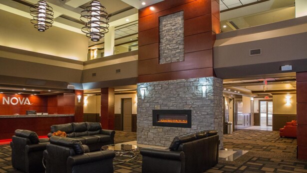 A lobby with a stone fireplace, leather sofas, and a reception desk labeled "NOVA".