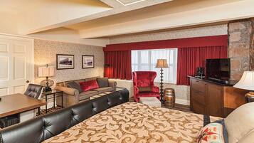 Une chambre d’hôtel comprenant un lit, un canapé, une table à manger, une télévision et une cheminée.