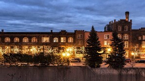 A historic building with arched windows and a central tower, surrounded by trees and street lamps. - Fitger's Inn (Duluth)